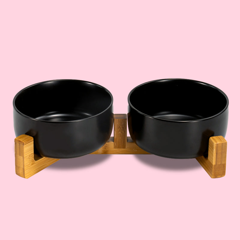 the front view of the black round ceramic dog bowl set in the pink background