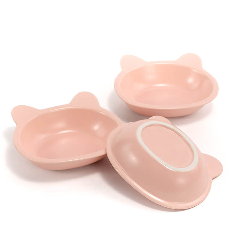 two front-facing, and one bottom-facing placed pink ceramic cat-shaped dishes