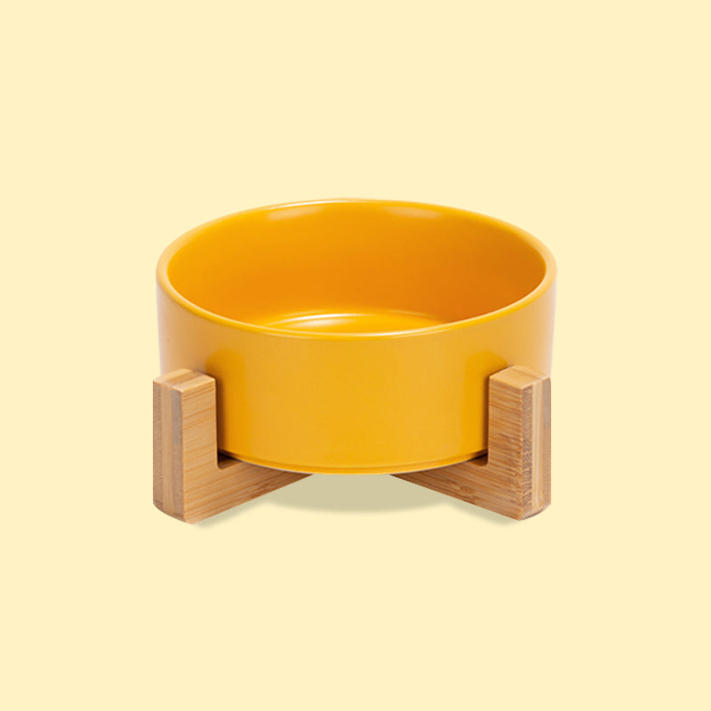 the front view of a cute yellow ceramic pet bowl with stand in the yellow background