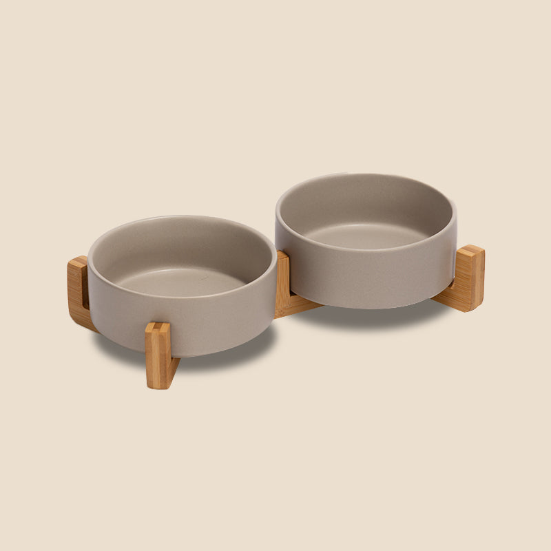 two cute grey pet bowls as a set on the bamboo stand in the grey background