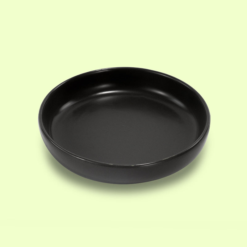 a black round cat dish in yellow background