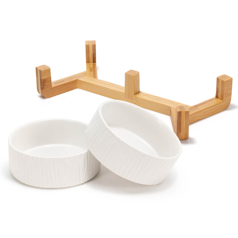 two white bark pattern dog bowls are in front of their bamboo stand