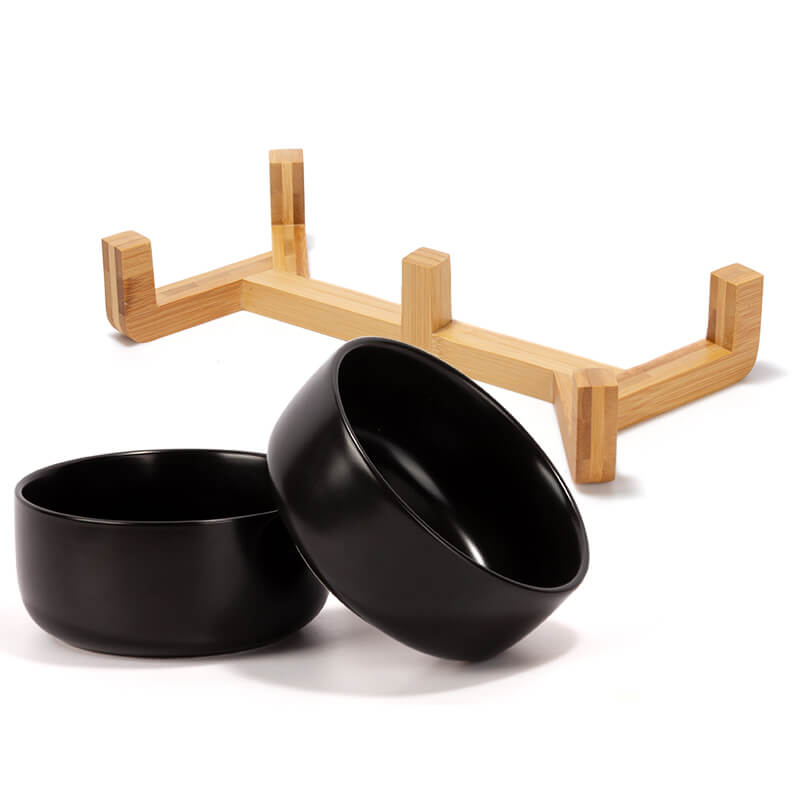 two black round ceramic dog bowls and their bamboo stand are placed separately