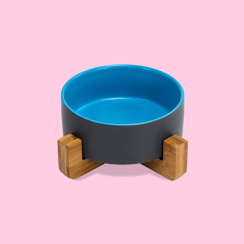 the front view of a grey-blue clashing dog bowl on the stand in the pink background