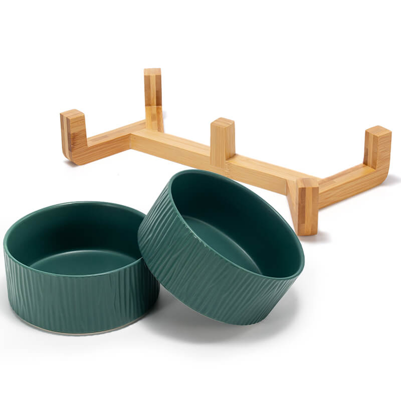 two green bark-patterned dog bowls are in front of their bamboo stand