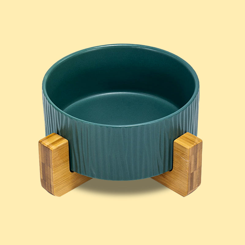 front view of a green bark pattern dog bowl with stand in yellow background