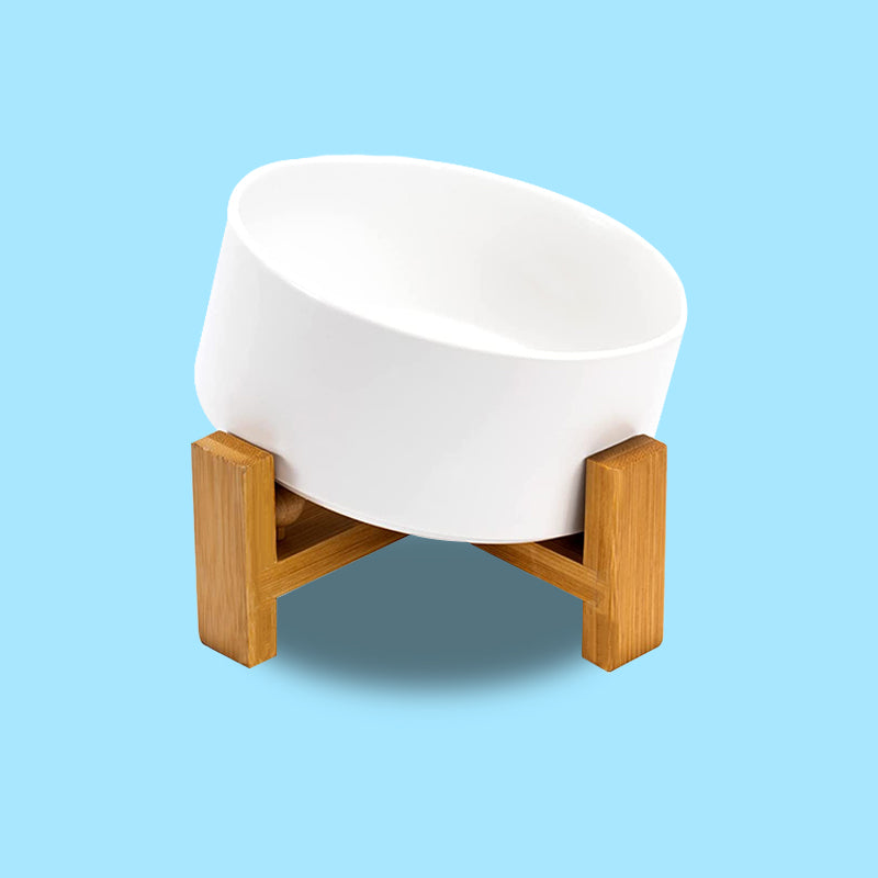 a white dog bowl tilted on the bamboo stand in blue background