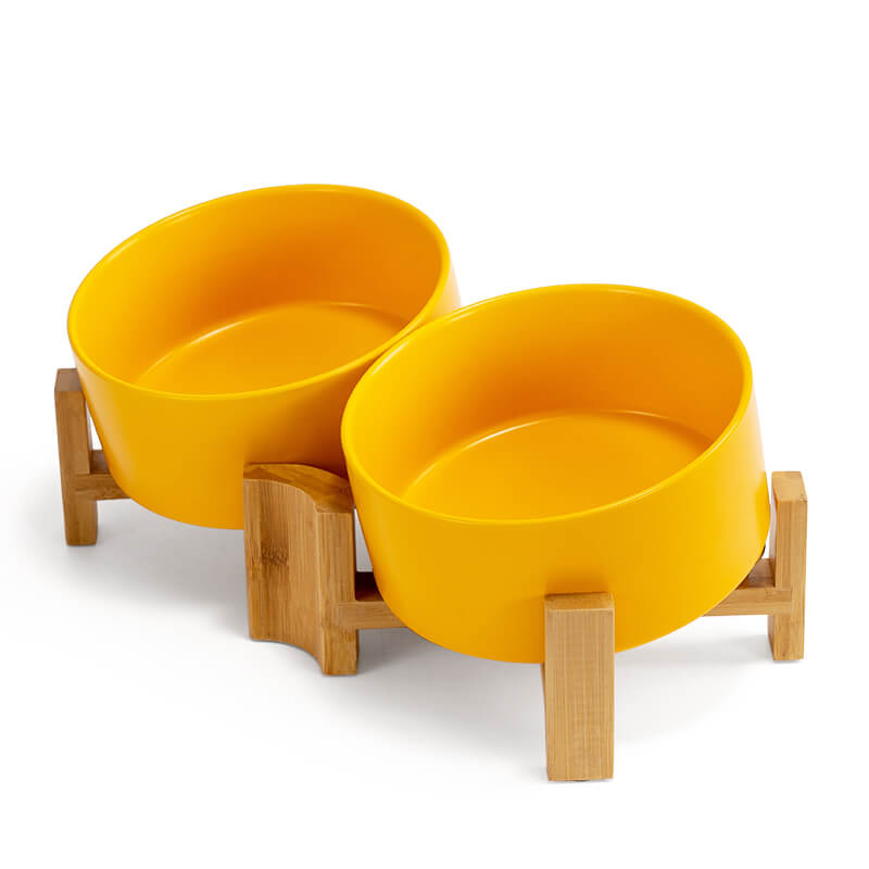the right-side view of 2 yellow pet bowls tilted on the bamboo stand