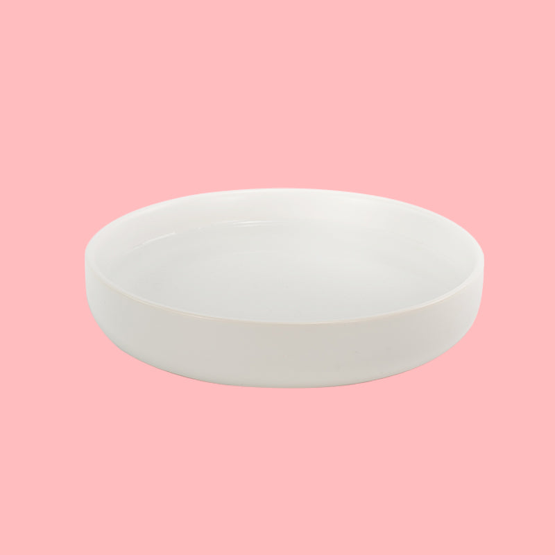 a white round cat dish in pink background